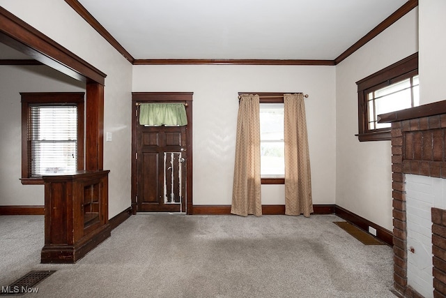 foyer entrance with light carpet, crown molding, a wealth of natural light, and a brick fireplace