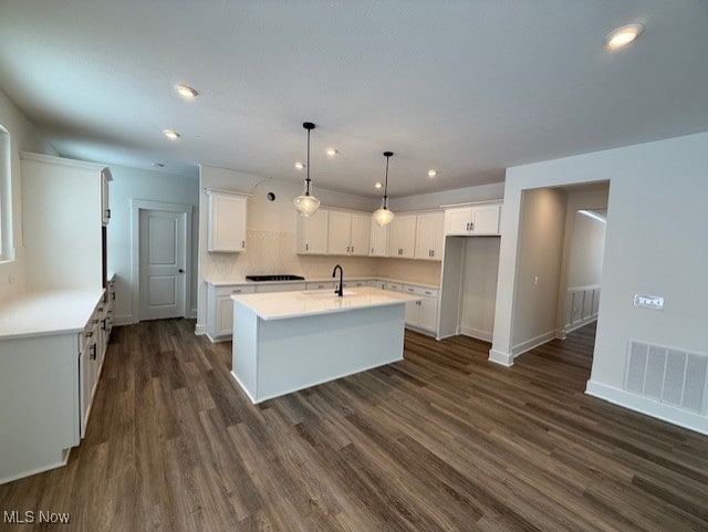 kitchen with white cabinetry, decorative light fixtures, and a kitchen island with sink