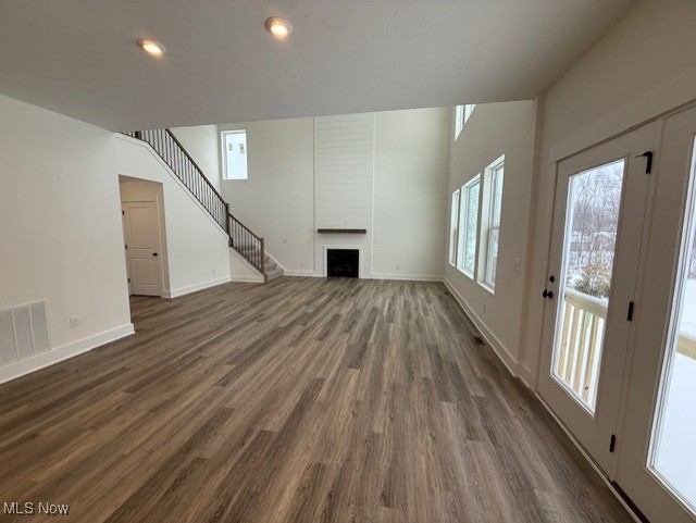 unfurnished living room with a large fireplace and dark hardwood / wood-style flooring