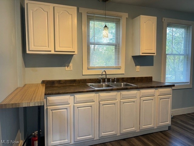 kitchen with white cabinets, sink, dark wood-type flooring, and decorative light fixtures