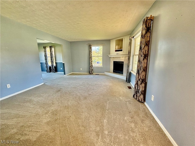 unfurnished living room featuring a textured ceiling and light colored carpet