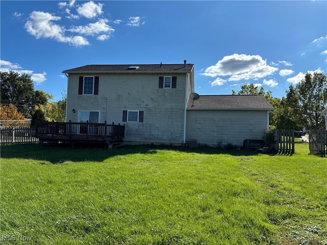 rear view of property featuring central air condition unit, a deck, and a lawn