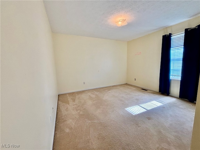 carpeted empty room featuring a textured ceiling