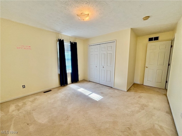 unfurnished bedroom with light carpet, a closet, and a textured ceiling