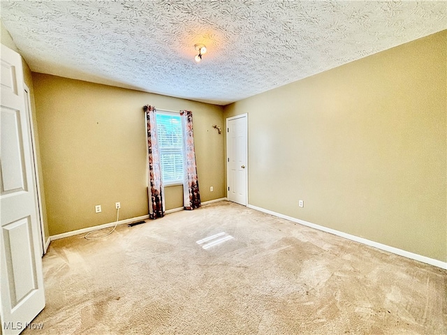 carpeted empty room featuring a textured ceiling