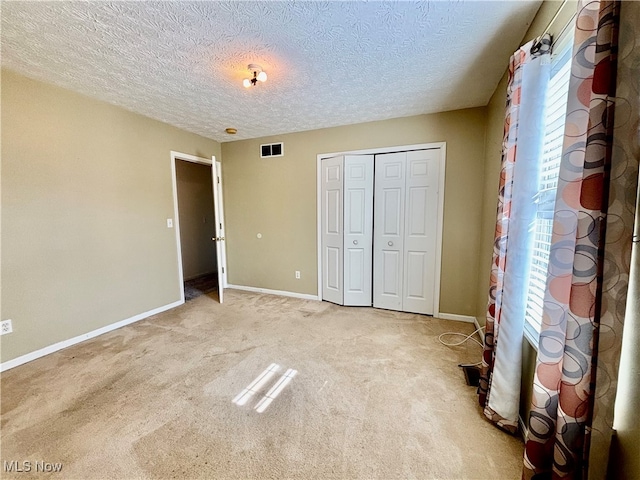 unfurnished bedroom with a textured ceiling, light colored carpet, and a closet