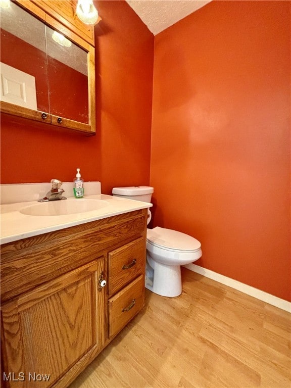 bathroom featuring vanity, toilet, and hardwood / wood-style flooring