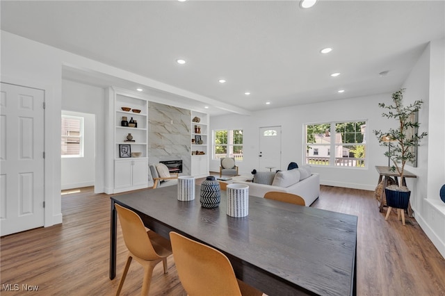 dining room featuring hardwood / wood-style flooring, a high end fireplace, and built in shelves