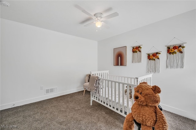 carpeted bedroom featuring a crib and ceiling fan