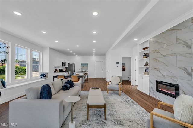 living room featuring light hardwood / wood-style flooring, a tiled fireplace, and built in shelves