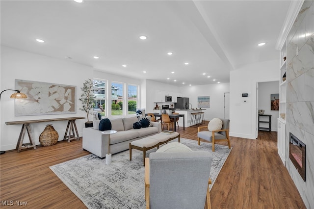 living room with a barn door, wood-type flooring, and a tile fireplace