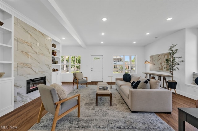 living room with beamed ceiling, a premium fireplace, built in shelves, and wood-type flooring