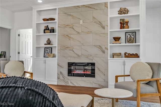 living room with a premium fireplace, hardwood / wood-style floors, and built in shelves