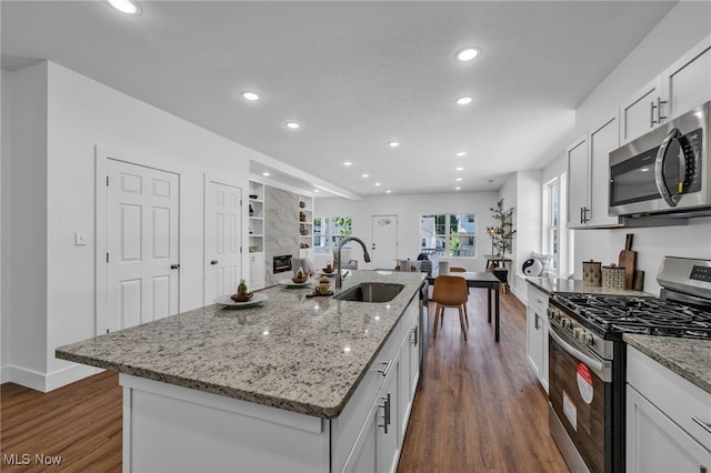 kitchen featuring an island with sink, appliances with stainless steel finishes, white cabinetry, dark wood-type flooring, and sink