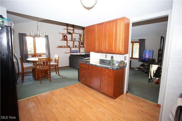 kitchen featuring a wealth of natural light, black fridge, hanging light fixtures, and light wood-type flooring