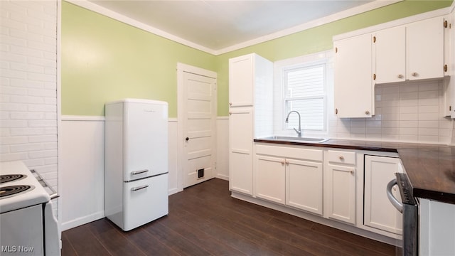 kitchen with white appliances, dark wood-type flooring, white cabinets, crown molding, and sink