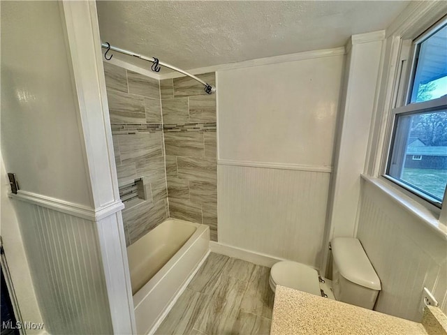 full bathroom featuring vanity, a textured ceiling, tiled shower / bath combo, hardwood / wood-style flooring, and toilet