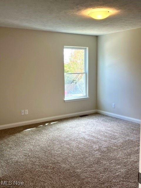 empty room with a textured ceiling and carpet floors