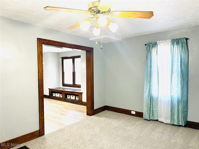 spare room featuring a textured ceiling, light colored carpet, and ceiling fan