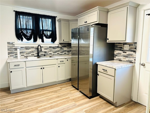 kitchen with light hardwood / wood-style flooring, sink, and stainless steel fridge