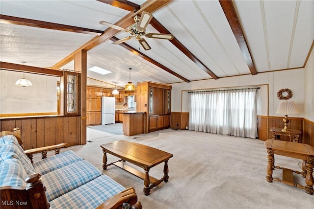 living room with lofted ceiling with beams, wood walls, light colored carpet, and ceiling fan