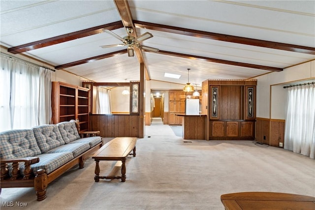 carpeted living room featuring lofted ceiling with beams, ceiling fan, and wooden walls