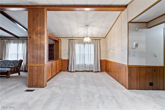 interior space with lofted ceiling with beams, a healthy amount of sunlight, hanging light fixtures, and light carpet