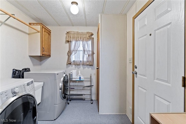 clothes washing area with cabinets, light carpet, a textured ceiling, and washer and clothes dryer