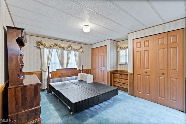 bedroom with multiple closets, a textured ceiling, and dark colored carpet