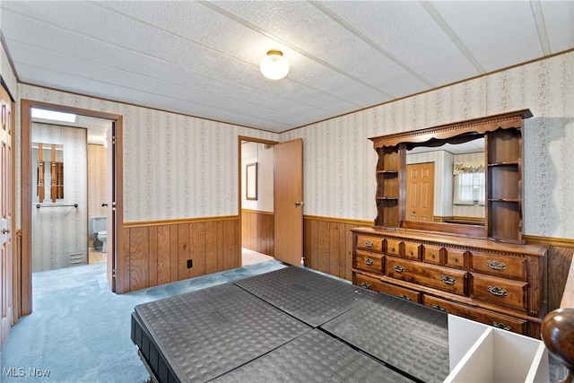 bedroom with light colored carpet, a textured ceiling, and wooden walls