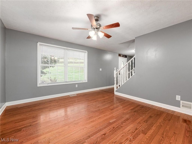 3905 E Greenwood, Zanesville, OH 43701 - empty room with ceiling fan, stairway, wood finished floors, baseboards, and a textured ceiling
