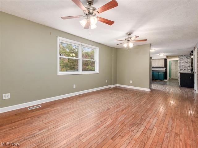 unfurnished living room with ceiling fan, hardwood / wood-style flooring, and a textured ceiling