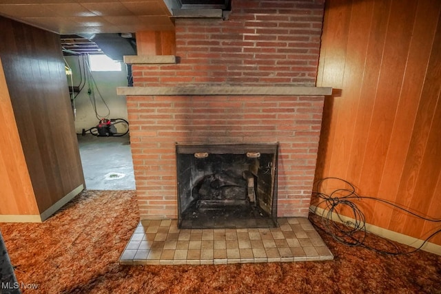 interior details featuring wood walls, carpet, and a brick fireplace