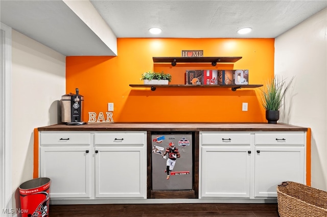 bar with white cabinetry, a textured ceiling, dark hardwood / wood-style flooring, and stainless steel fridge