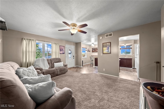 living room with light carpet, a textured ceiling, sink, and ceiling fan