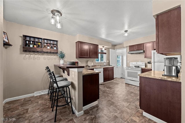 kitchen with kitchen peninsula, a breakfast bar, light stone countertops, sink, and white appliances