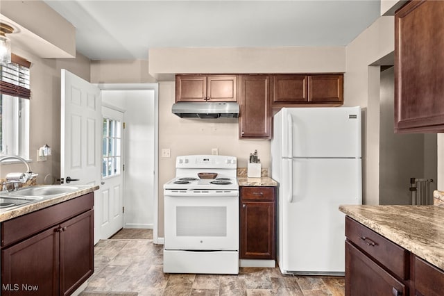 kitchen featuring sink, light stone countertops, dark brown cabinetry, and white appliances