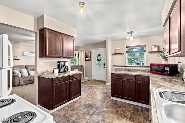 kitchen with dark brown cabinetry, sink, and white appliances