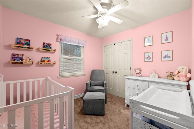 bedroom with light colored carpet, a closet, a crib, and ceiling fan