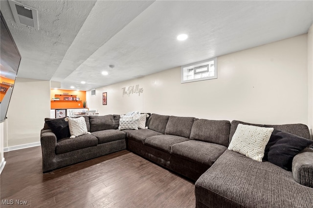 living room with a textured ceiling and dark hardwood / wood-style flooring