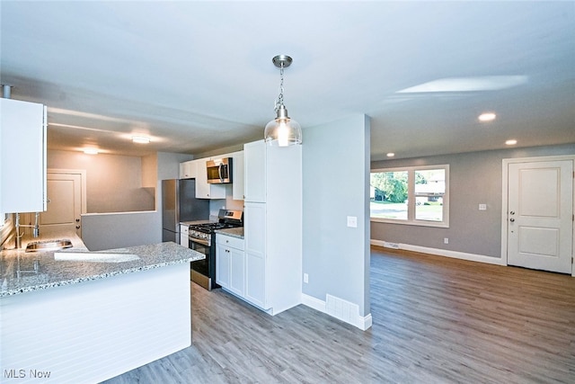 kitchen with white cabinetry, stainless steel appliances, and hardwood / wood-style floors