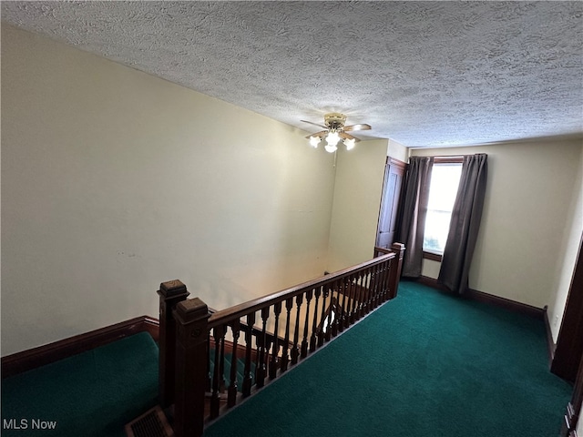 hallway with a textured ceiling and carpet floors