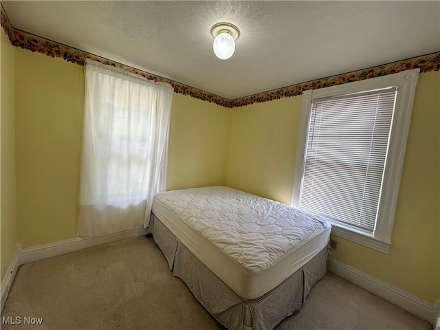 bedroom featuring light carpet and a textured ceiling