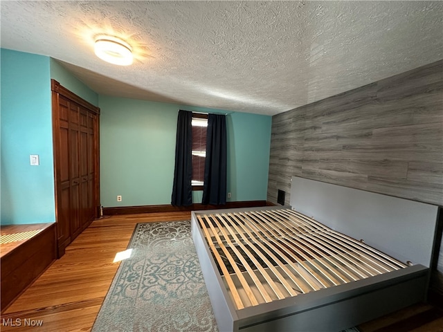 unfurnished bedroom with a closet, a textured ceiling, and light wood-type flooring