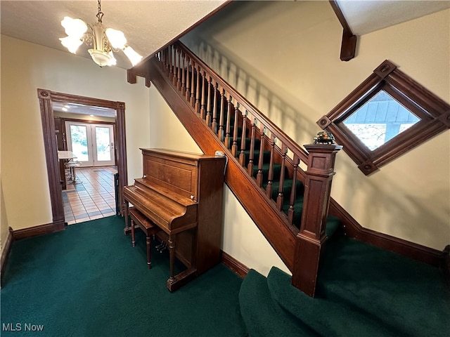 stairs with an inviting chandelier, carpet floors, a textured ceiling, and french doors