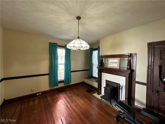 interior space featuring a textured ceiling, a wood stove, and dark hardwood / wood-style flooring