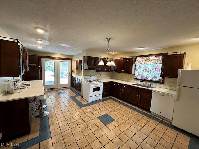 kitchen featuring white appliances, sink, a textured ceiling, decorative light fixtures, and light tile patterned floors