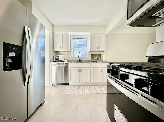 kitchen with appliances with stainless steel finishes, light hardwood / wood-style flooring, white cabinetry, and sink