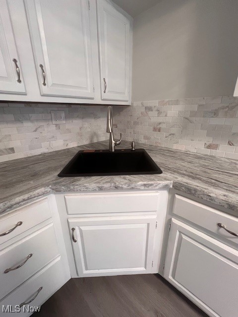 kitchen with dark hardwood / wood-style flooring, tasteful backsplash, sink, and white cabinets