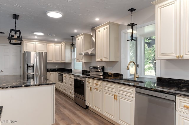 kitchen with appliances with stainless steel finishes, light hardwood / wood-style flooring, pendant lighting, and dark stone countertops